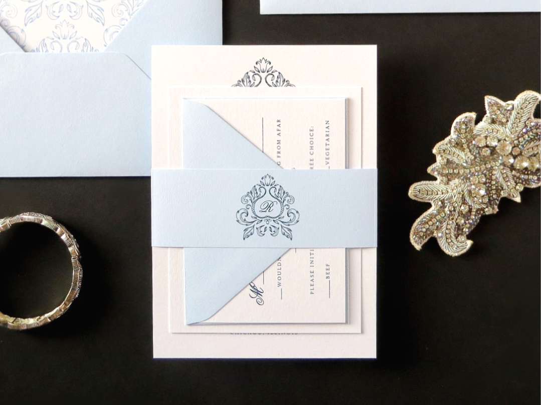 ELEGANT AND FORMAL ORNATE MONOGRAM CREST WEDDING INVITATION IN WHITE, PALE SERENITY BLUE AND ICE SILVER