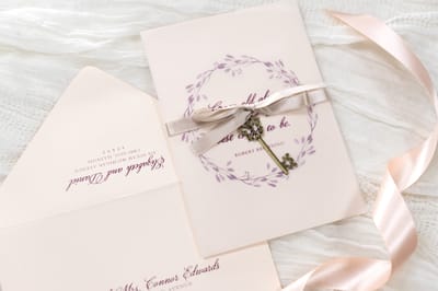 elegant and formal vintage style key charm wedding invitation in blush, opal shimmer, and burgundy with vellum sheet and satin ribbon