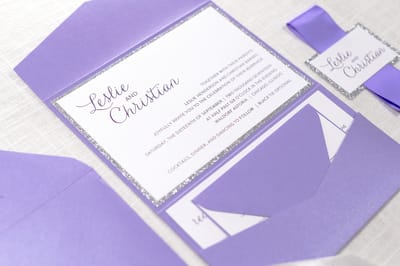 elegant and formal white, silver glitter and purple shimmer pocketfold wedding invitation with satin ribbon belly band and monogram