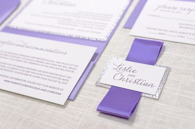 elegant and formal white, silver glitter and purple shimmer pocketfold wedding invitation with satin ribbon belly band and monogram